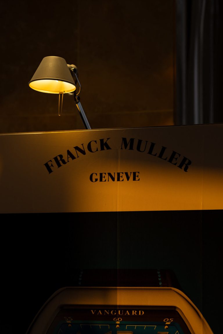 Franck Muller Genève sign under a desk lamp, photographed by Indirect Media