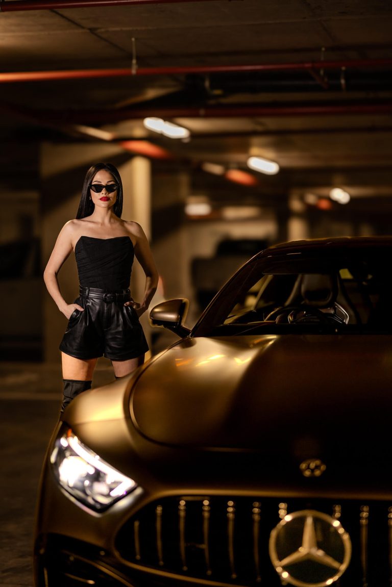 Model in black beside a Mercedes-AMG in an underground garage, photographed by Indirect Media
